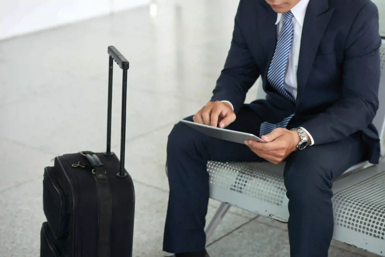 Detail of a seated businessman, holding a laptop and a trolley in front of him